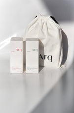 Two white boxes with the "Arq" logo, one labeled "Glow" and the other "Detox." Both are next to a white drawstring pouch with the "Arq" logo.