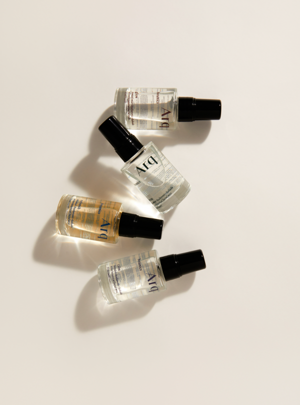 Four bottles of arq perfume arranged neatly on a white surface, showcasing vibrant hues and sleek designs.