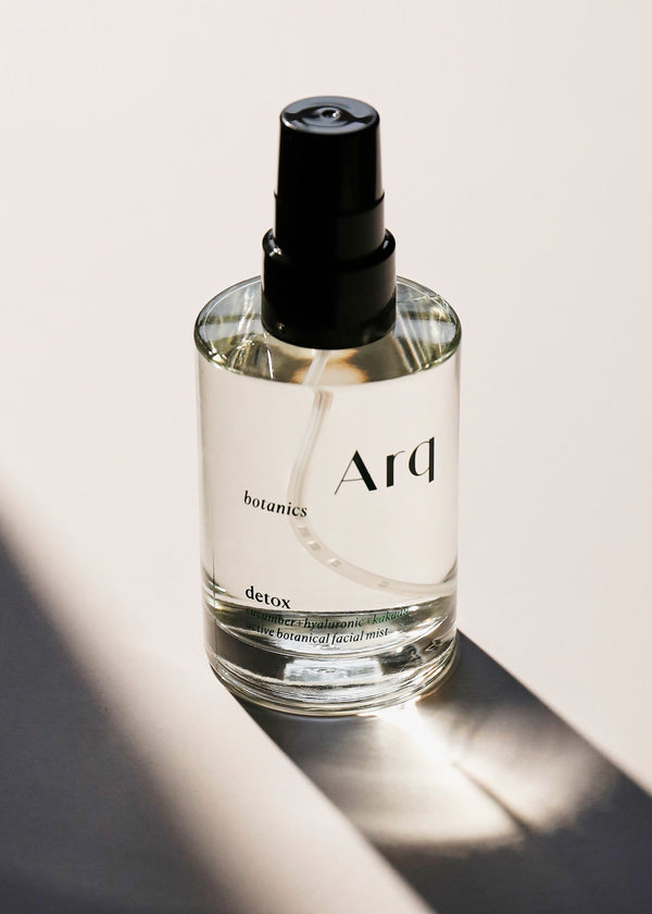 A glass bottle of Arq Botanics Detox Cucumber Hyaluronic Facial Mist with a black spray pump, sitting on a white surface.